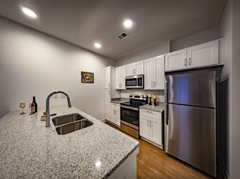 A kitchen with a granite countertop and stainless steel appliances at Wesley Place Apartments in Indianapolis, IN.